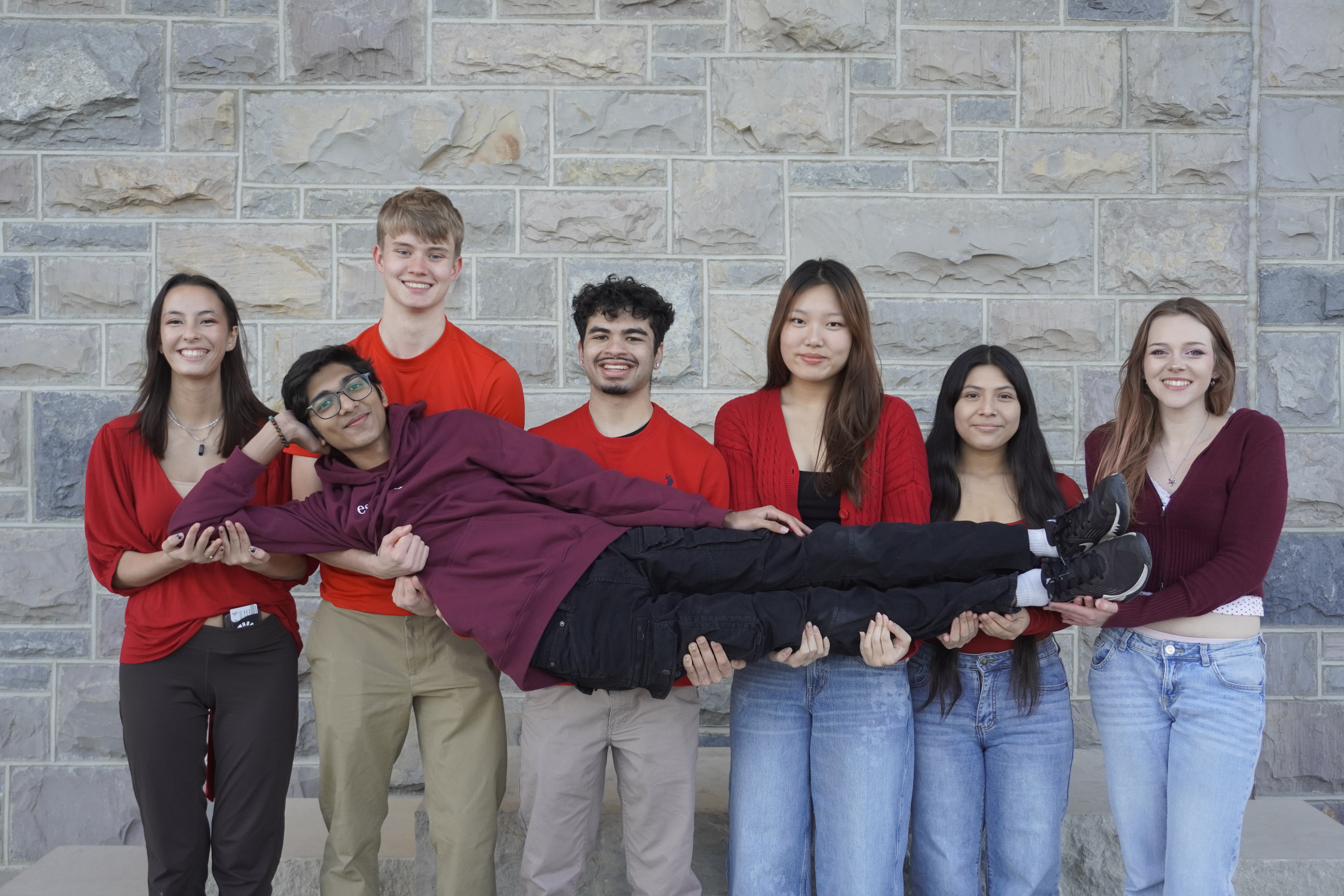 Six team members in line carrying seventh member who is laying down