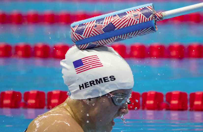 Swimmer in water getting tapped by foam stick
